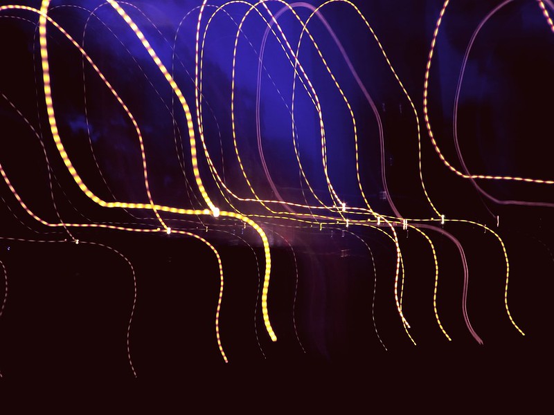 Image of squiggles of light against a dark black and purple background.