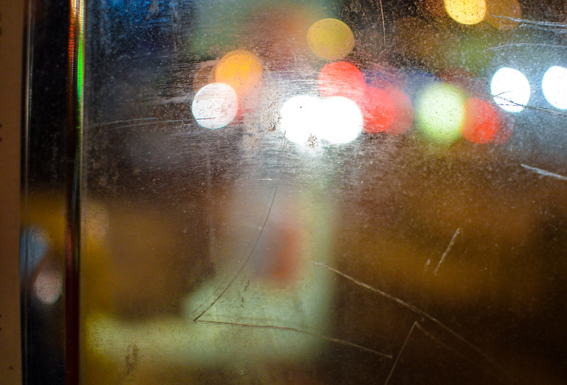 Image of scratched surface reflecting blurred, multicolored lights.