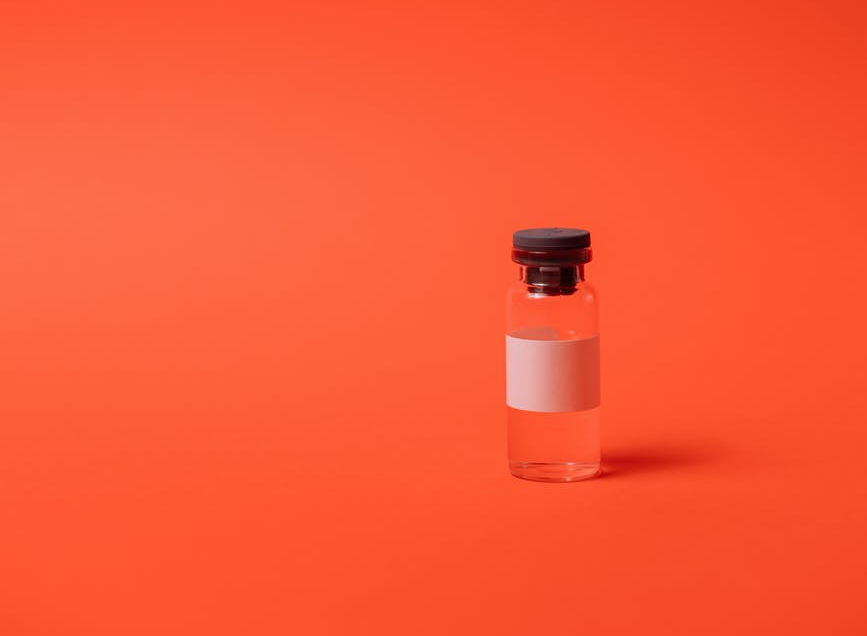 Glass vial on red-orange background